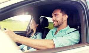 Happy couple driving in the sunshine