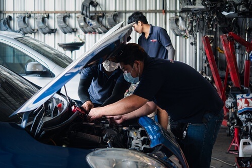 Tune Up with Horeb Auto Repair, Houston Tx; 3 Hispanic auto mechanics wearing face masks giving a car in the shop a tune up